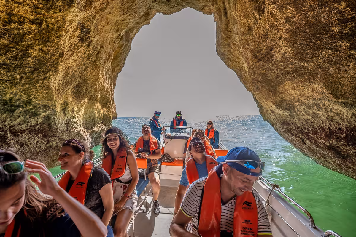 Tourists enjoying a boat ride through a cave on a Benagil tour from Portimão, wearing orange life jackets.