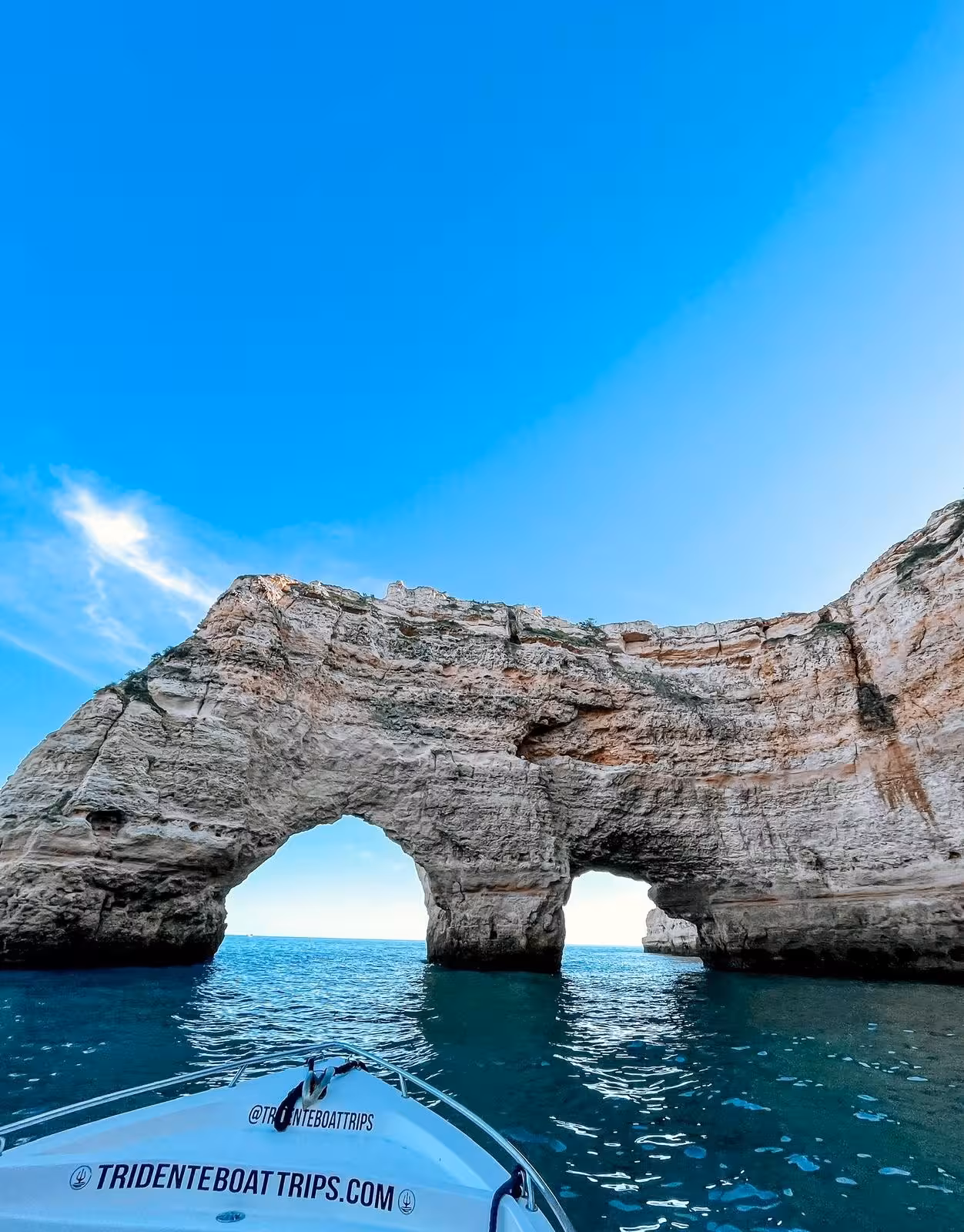 Boat approaches dramatic double sea arch cliffs near Benagil Cave on a private Algarve coastal tour from the water