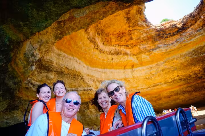 Happy travelers in life jackets inside Benagil Cave on Algarve private tour from Lisbon with boat trip