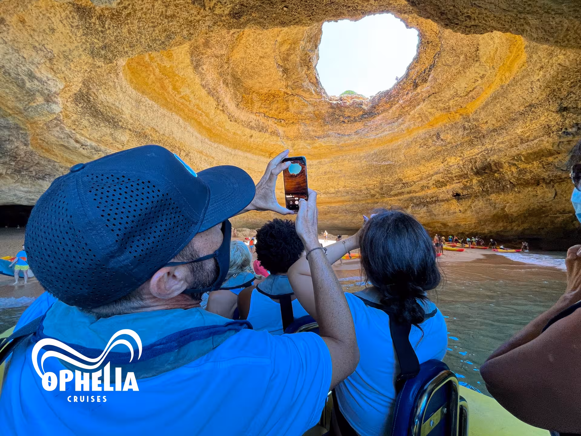 Visitors capture the stunning skylight of Benagil Cave from a boat, highlighting Algarve's natural beauty and adventure.