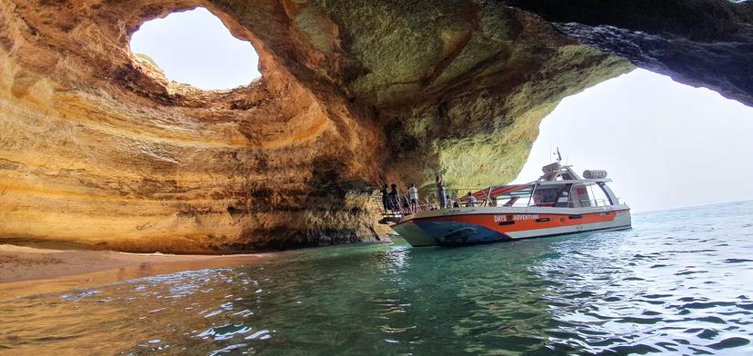 Catamaran entering the iconic Benagil Cave with its famous skylight opening on an Algarve boat tour from Lagos Portugal