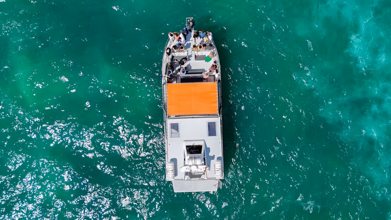 Aerial view of a catamaran with tourists sailing on turquoise Atlantic waters during Benagil Cave boat tour from Lagos