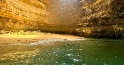 Hidden golden-sand beach and emerald water inside Benagil Cave on an Algarve coastal boat tour in southern Portugal
