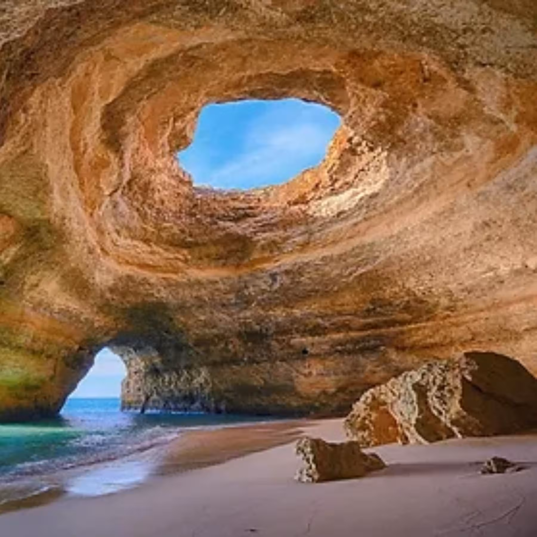 Interior view of iconic Benagil Cave Algarve showing sandy beach turquoise water and natural rock skylight