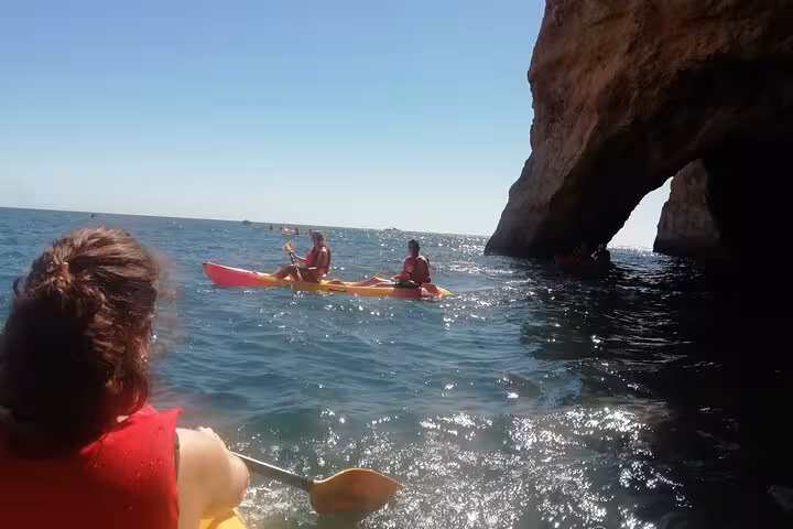 Guided kayak tour near Benagil sea caves, paddling past Algarve cliffs and a rocky arch on the Atlantic