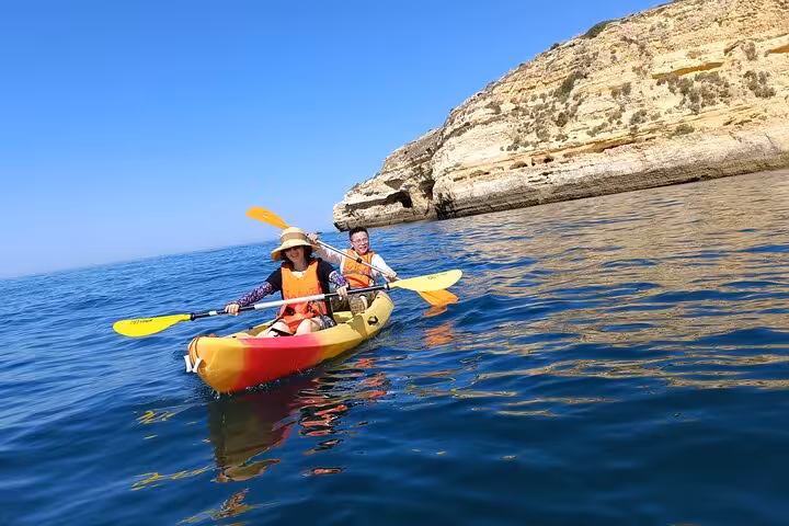Two-person kayak paddling along Algarve cliffs on a Benagil sea caves guided kayak tour in Portugal