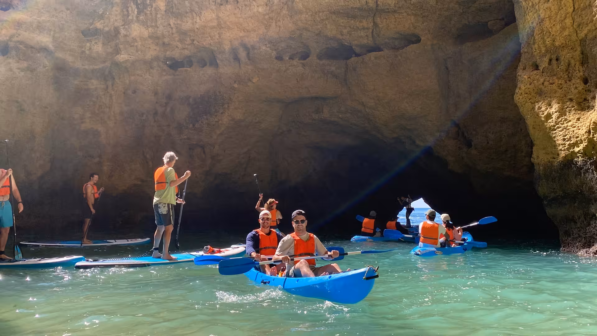 Group kayaking and paddleboarding into Benagil sea cave at sunrise, exploring Algarve’s hidden rock arches and turquoise water