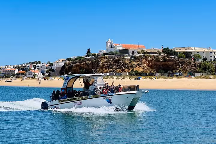 Boat approaching Algarve coastal rock arches and caves