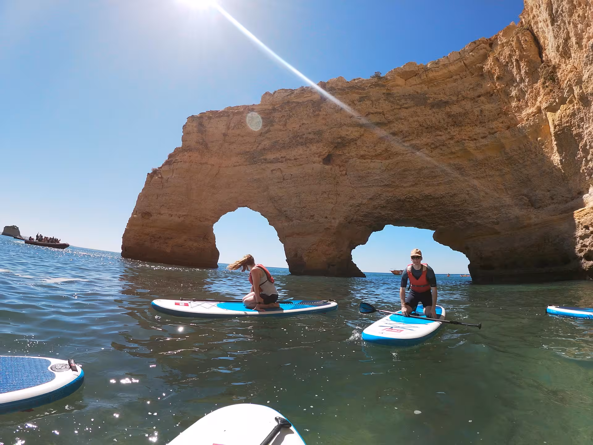 Paddleboarders explore Benagil Cave arches on a sunny Algarve coast tour, gliding over calm Atlantic waters near Lagos