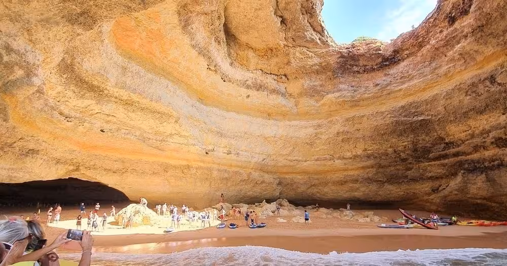 Tourists explore the stunning Benagil Cave from a private boat, capturing the breathtaking limestone formations.
