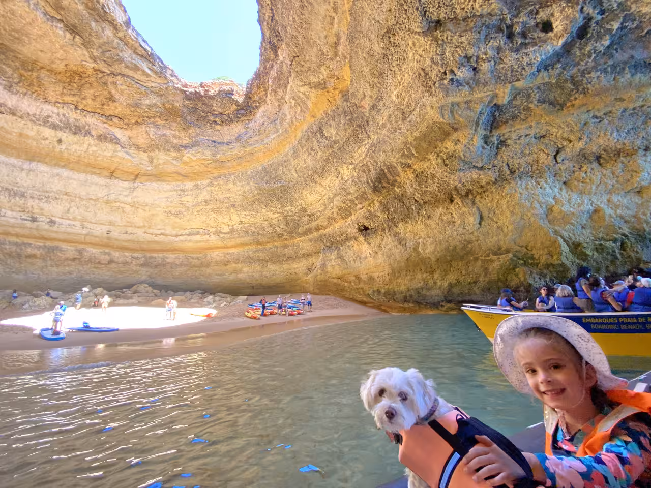 Family-friendly Benagil Cave private boat tour with child and dog in life jackets, kayaks and yellow boat on Algarve coast