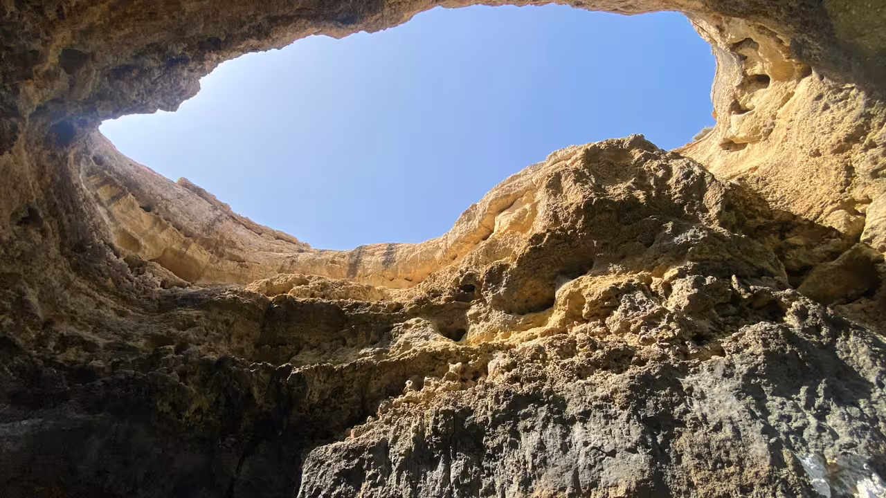 View up to the skylight of Benagil Cave on an Algarve caves and coastline boat tour under blue sky