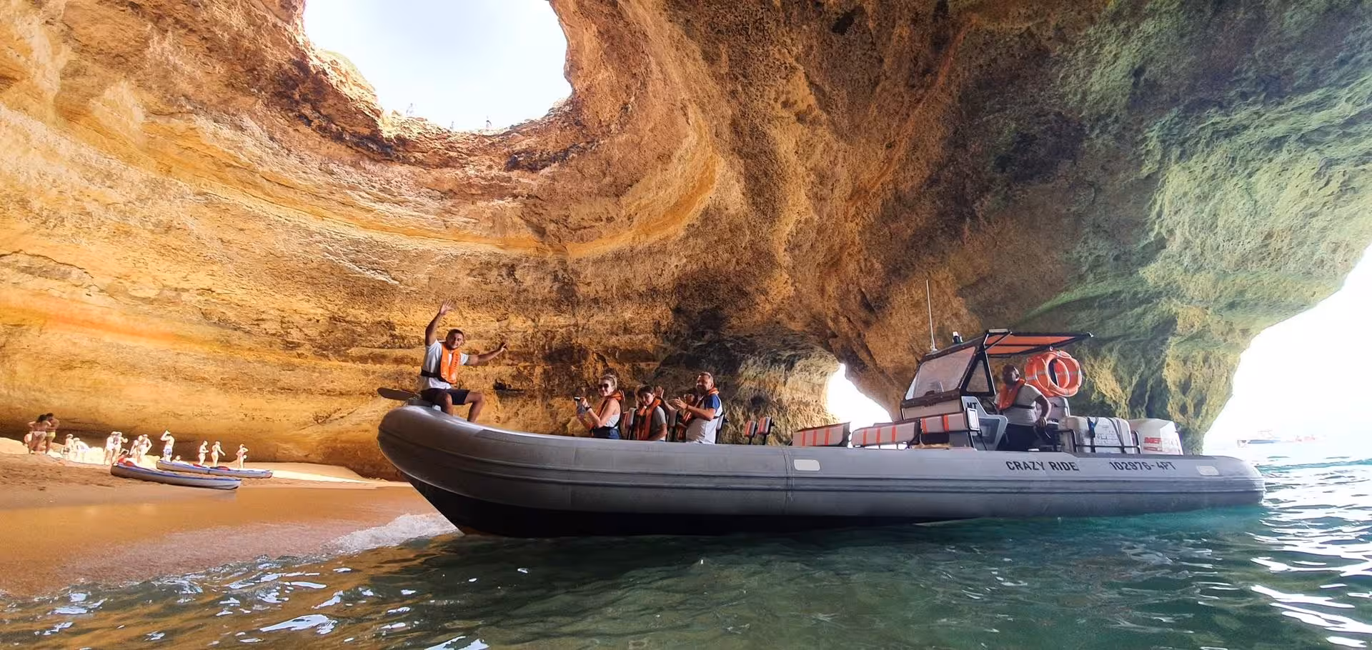 Tourists on a Crazy Ride speed boat inside Benagil Cave enjoying the famous sea cave tour in Algarve Portugal