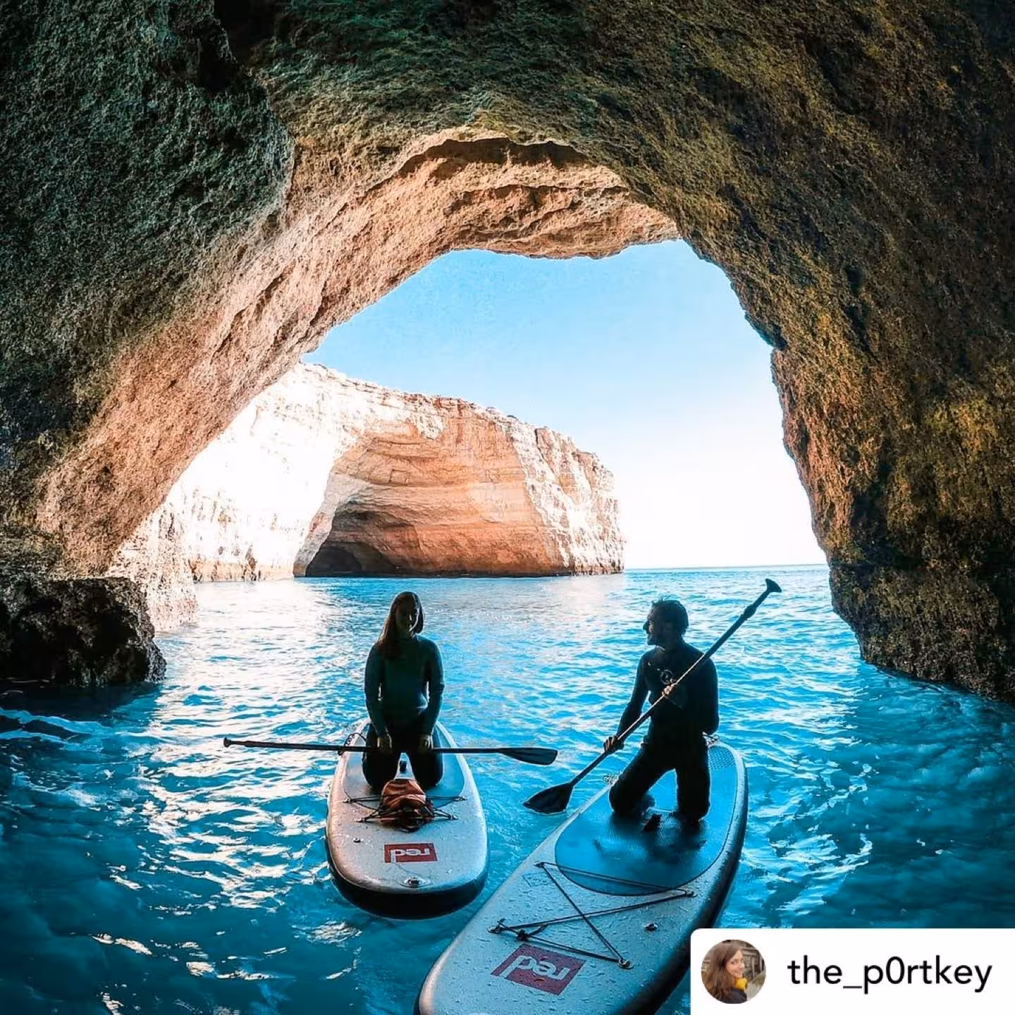 Couple on stand up paddleboards inside Benagil Cave, admiring turquoise Algarve waters on a guided SUP adventure