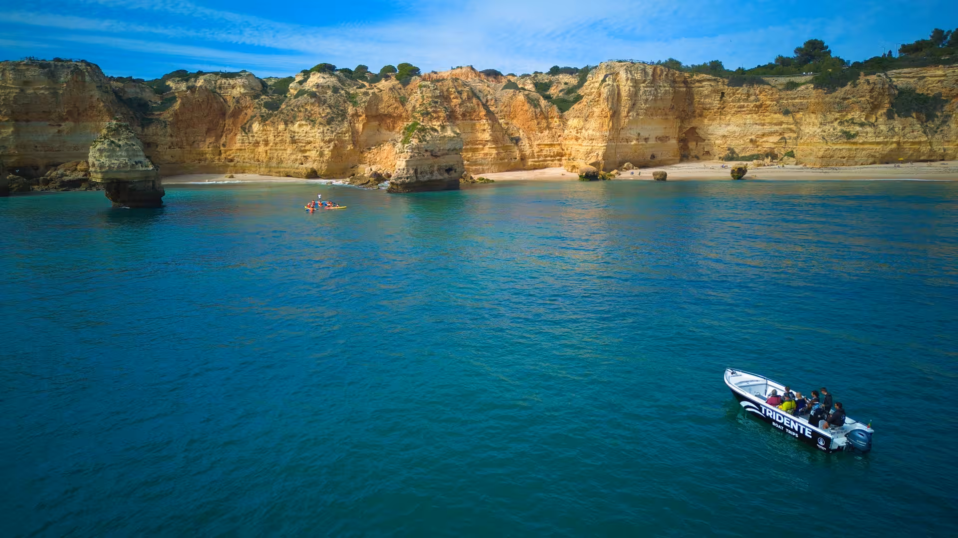 Tridente boat and kayakers exploring Algarve cliffs and secluded beaches on an Essential Benagil Cave coastal cruise