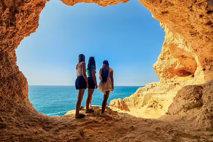Three people admire the ocean view from inside the stunning Benagil Cave on the Algarve Coast tour from Faro.