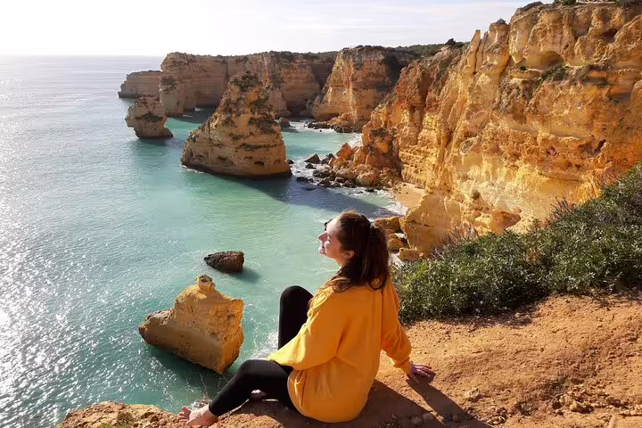 Person enjoying the breathtaking cliffs and turquoise waters of the Algarve Coast on a Benagil Cave tour from Faro.