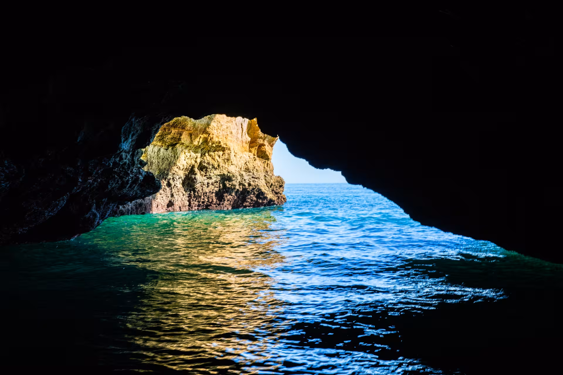 View from inside Benagil sea cave looking out to turquoise Atlantic Ocean and sunlit Algarve cliffs on a guided boat tour