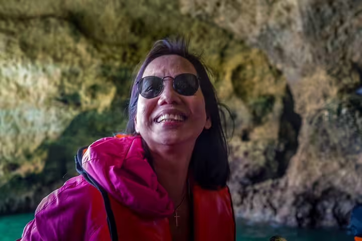 Smiling tourist enjoys a boat tour inside the stunning Benagil Caves during a full-day private Algarve adventure from Lisbon.