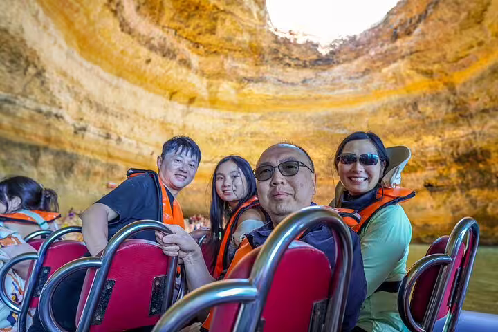 Tourists enjoy a scenic boat trip inside the stunning Benagil Caves during an Algarve private tour from Lisbon.