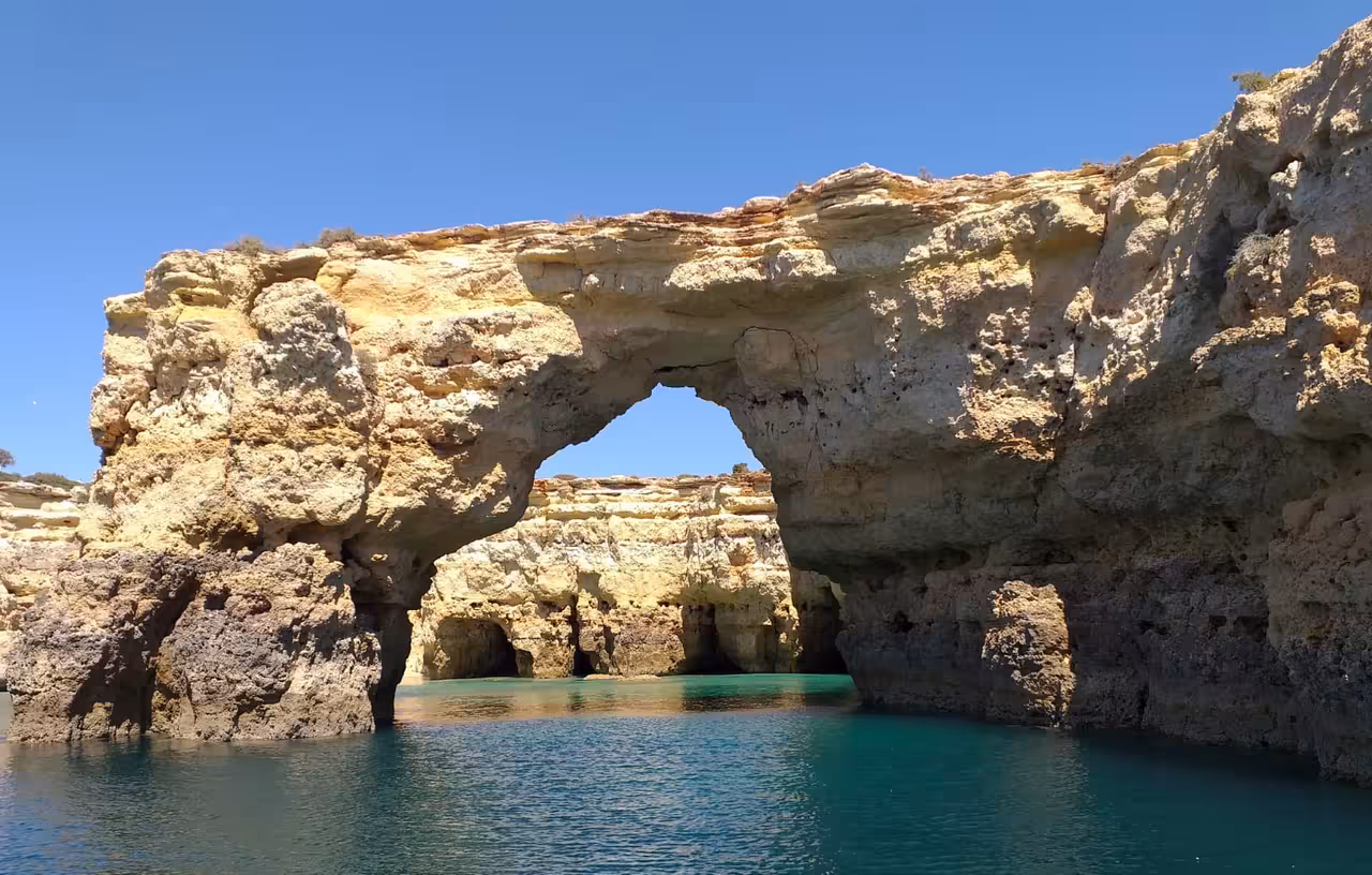 Algarve sea arch and hidden grotto on Benagil Caves boat tour from Albufeira, calm blue water and cliffs