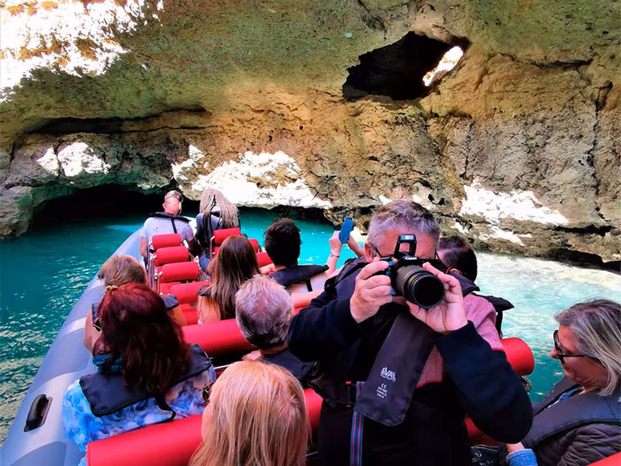 Passengers in an Albufeira rib boat cruise into Algarve sea caves, photographing turquoise water on Benagil tour