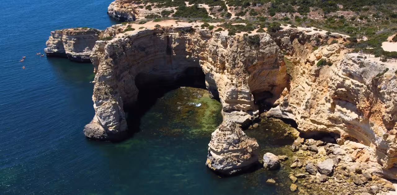 Drone view of Benagil sea caves and towering limestone cliffs rising above emerald Atlantic waters on the Algarve coast
