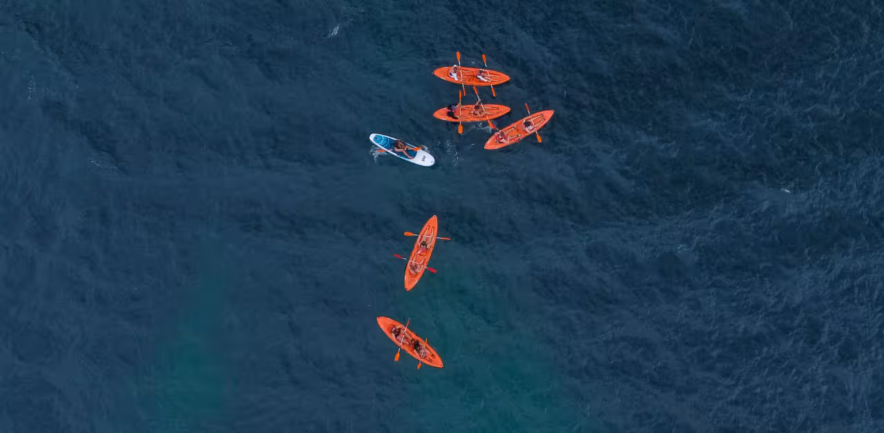 Aerial view of guided kayakers paddling in clear Atlantic waters on a Benagil Caves adventure tour in Algarve, Portugal