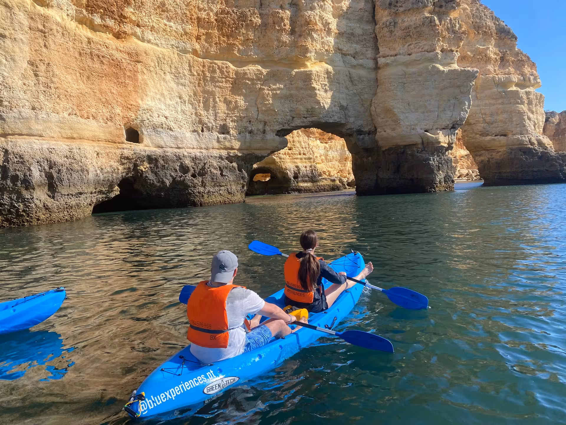 Couple kayaking along Algarve’s Benagil sea caves, paddling past golden limestone arches on a guided ocean adventure