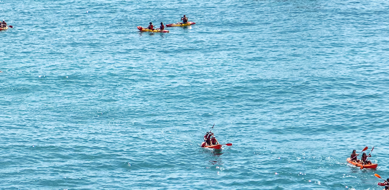 Small groups paddling red kayaks across clear Atlantic waters on a guided Benagil Caves sea kayaking tour in Algarve