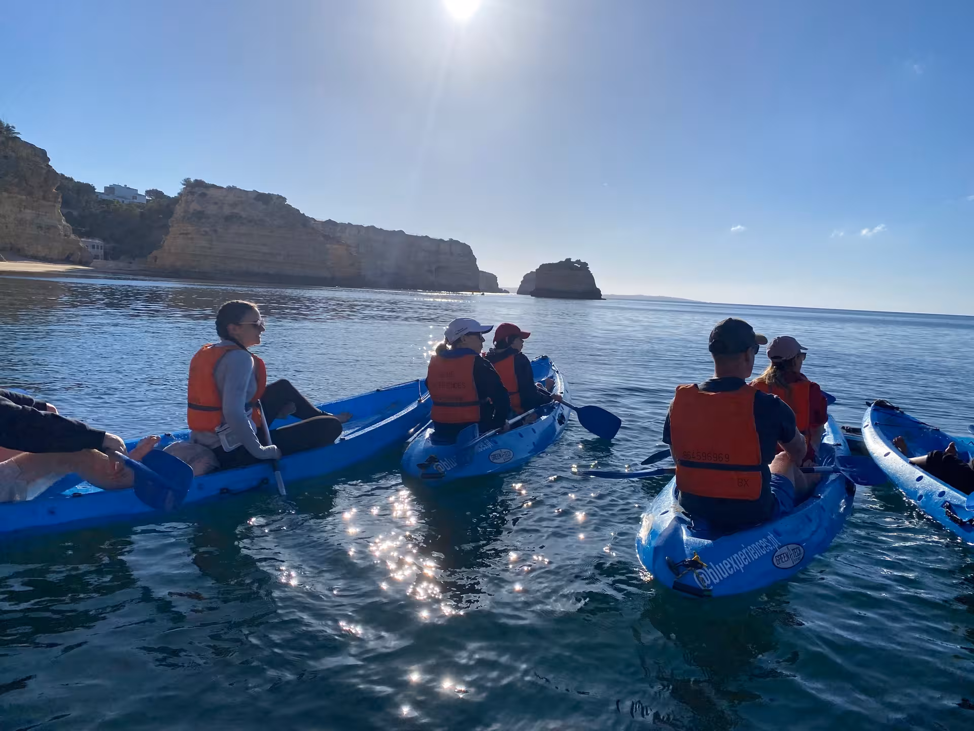Friends on sunrise Benagil kayaking tour pause offshore to admire Algarve cliffs and secluded beaches on a calm Atlantic morning