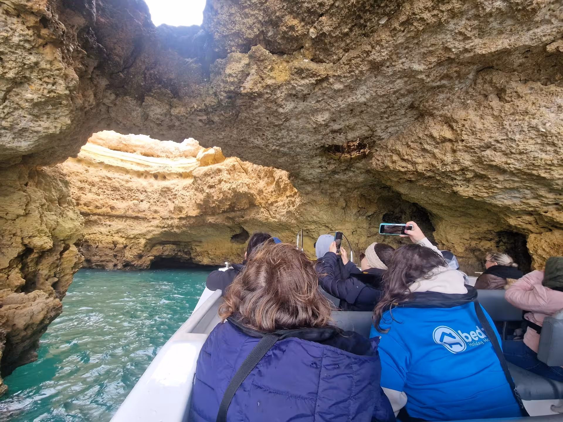 Tourists on Benagil & Dolphins cave boat tour cruising through dramatic Algarve sea grotto with turquoise water