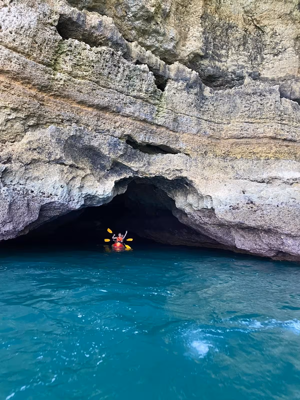 Kayaker entering a sea cave on turquoise Algarve water, adventure route with Benagil kayak rental and cave tour