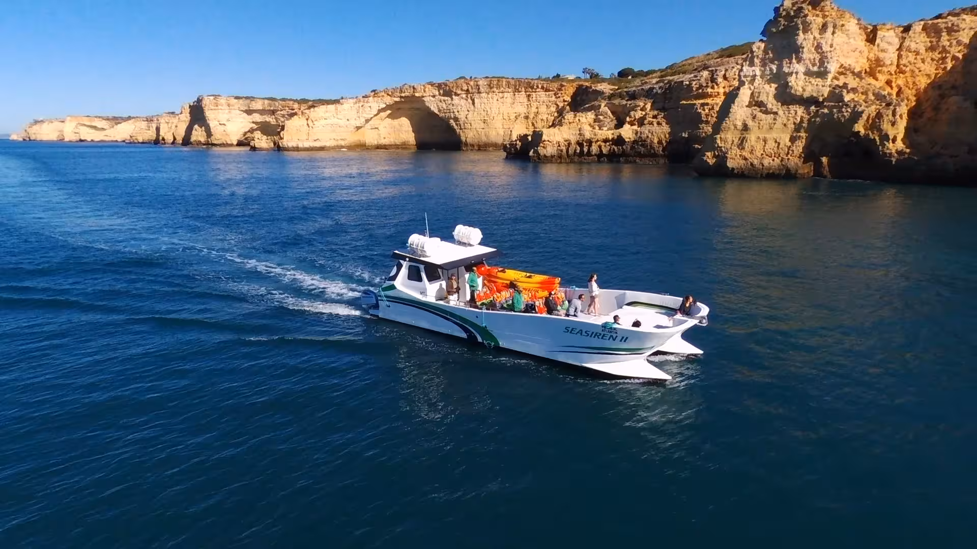 Benagil kayak tour support boat cruising along Algarve’s golden cliffs and crystal-clear Atlantic waters near Benagil Cave