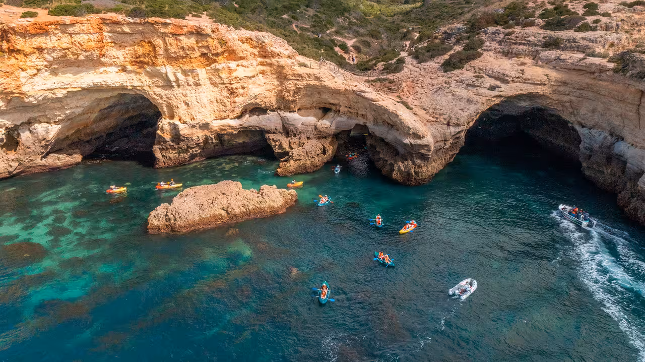 Aerial view of kayakers exploring Algarve sea caves near Benagil on a guided kayak tour in turquoise water