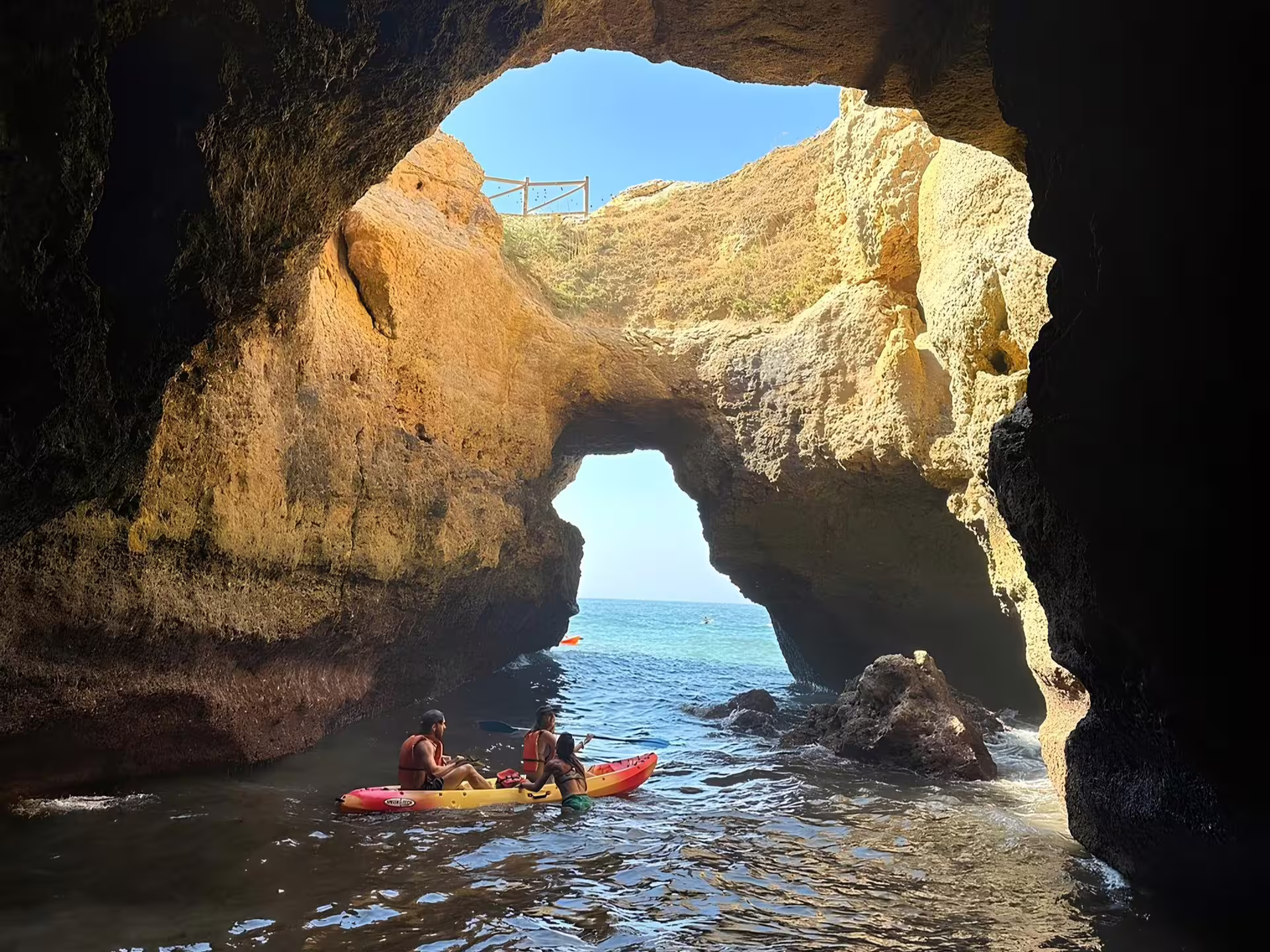 Adventurers in a kayak navigate through a picturesque archway on the Benagil Kayak Tour with expert local guidance.