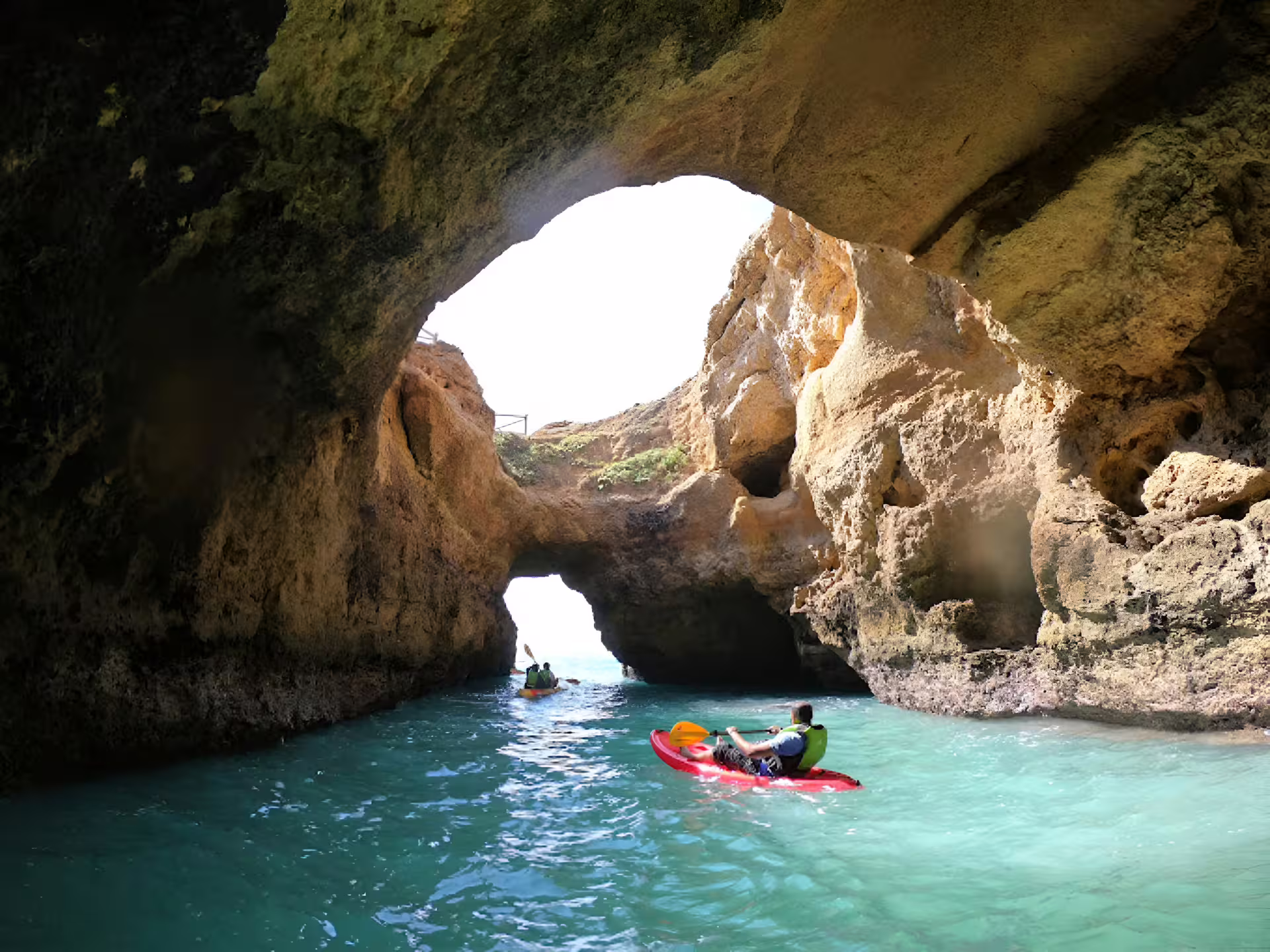 Adventurers paddle through a breathtaking cave on a Benagil kayak tour, showcasing serene waters and natural beauty.