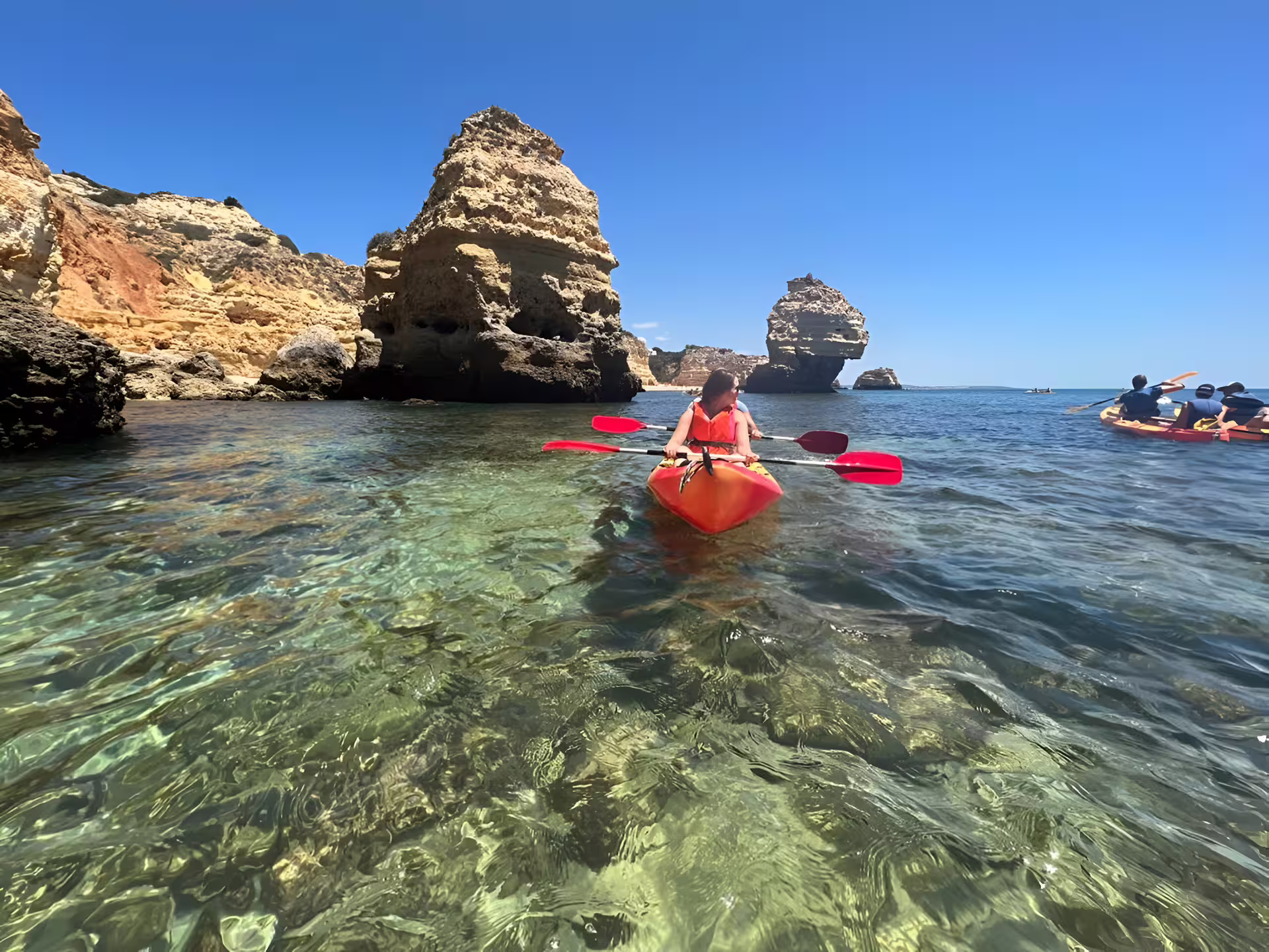 Solo kayaker navigating scenic rocky formations on a Benagil Kayak Tour, enjoying a guided adventure in small groups.