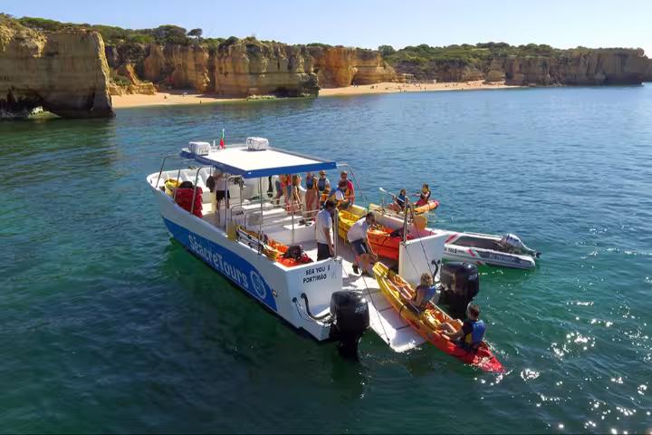 Support boat launching kayaks for Benagil Kayak Tour along Algarve cliffs and calm ocean near sandy beach
