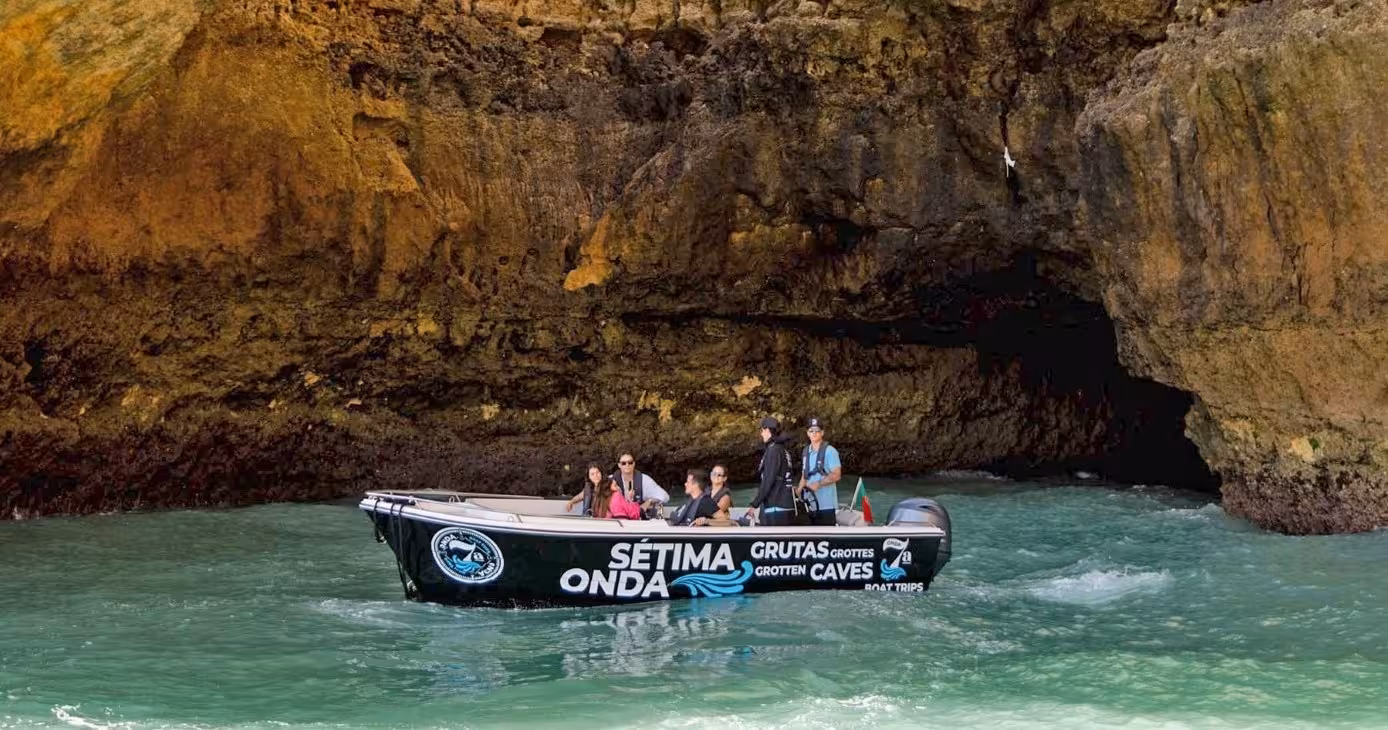 Small Benagil Plus 1H30 boat tour gliding into Algarve sea cave, visitors admiring dramatic golden cliffs and turquoise water