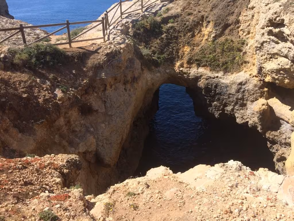 Natural sea arch and rugged cliffs above deep blue Atlantic waters on the Benagil coastal walking route in Algarve Portugal
