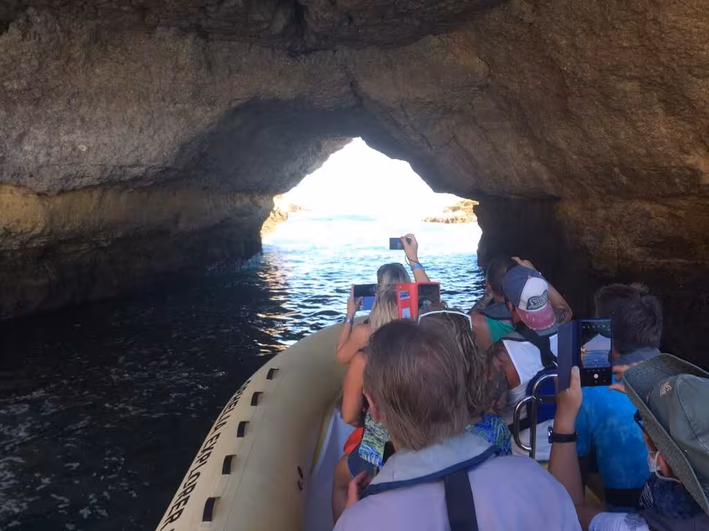 Tourists on Benagil sea cave boat tour photographing rock tunnel and Atlantic views along the dramatic Algarve coastline