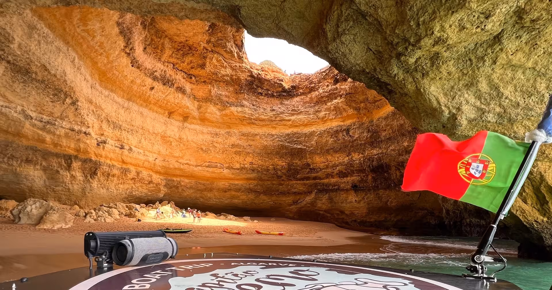 Inside Benagil Sea Cave Algarve on boat tour, skylight dome, beach and Portugal flag at cave entrance