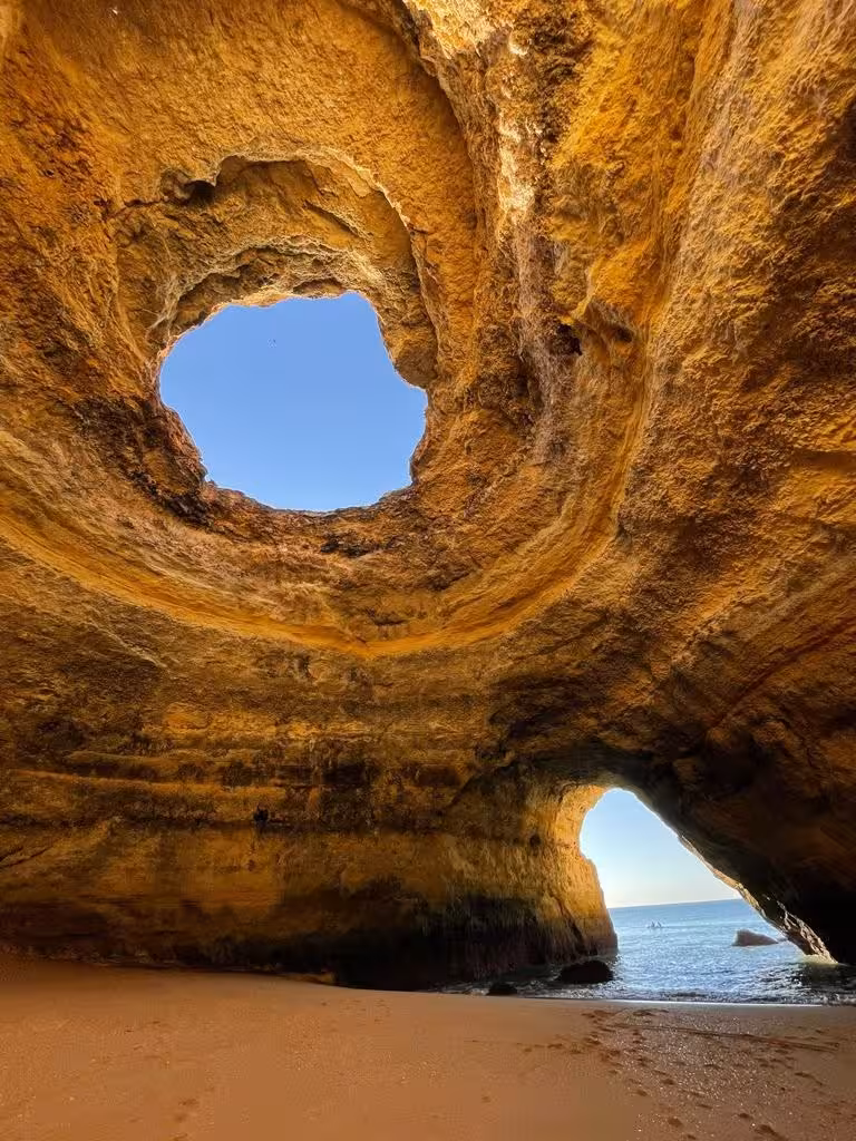 Sea cave with skylight opening and sandy beach, ideal stop on Algarve coastal kayak cave tour in Portugal