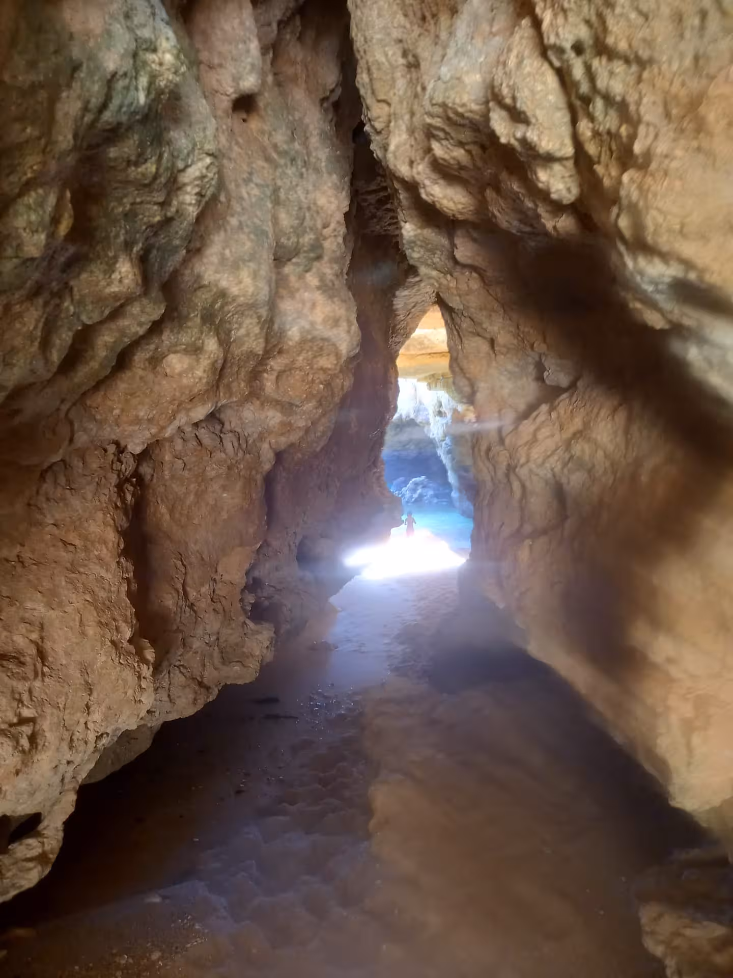Sea cave passage opening to a sunlit beach, a highlight stop on coastal kayak tours and guided cave exploration