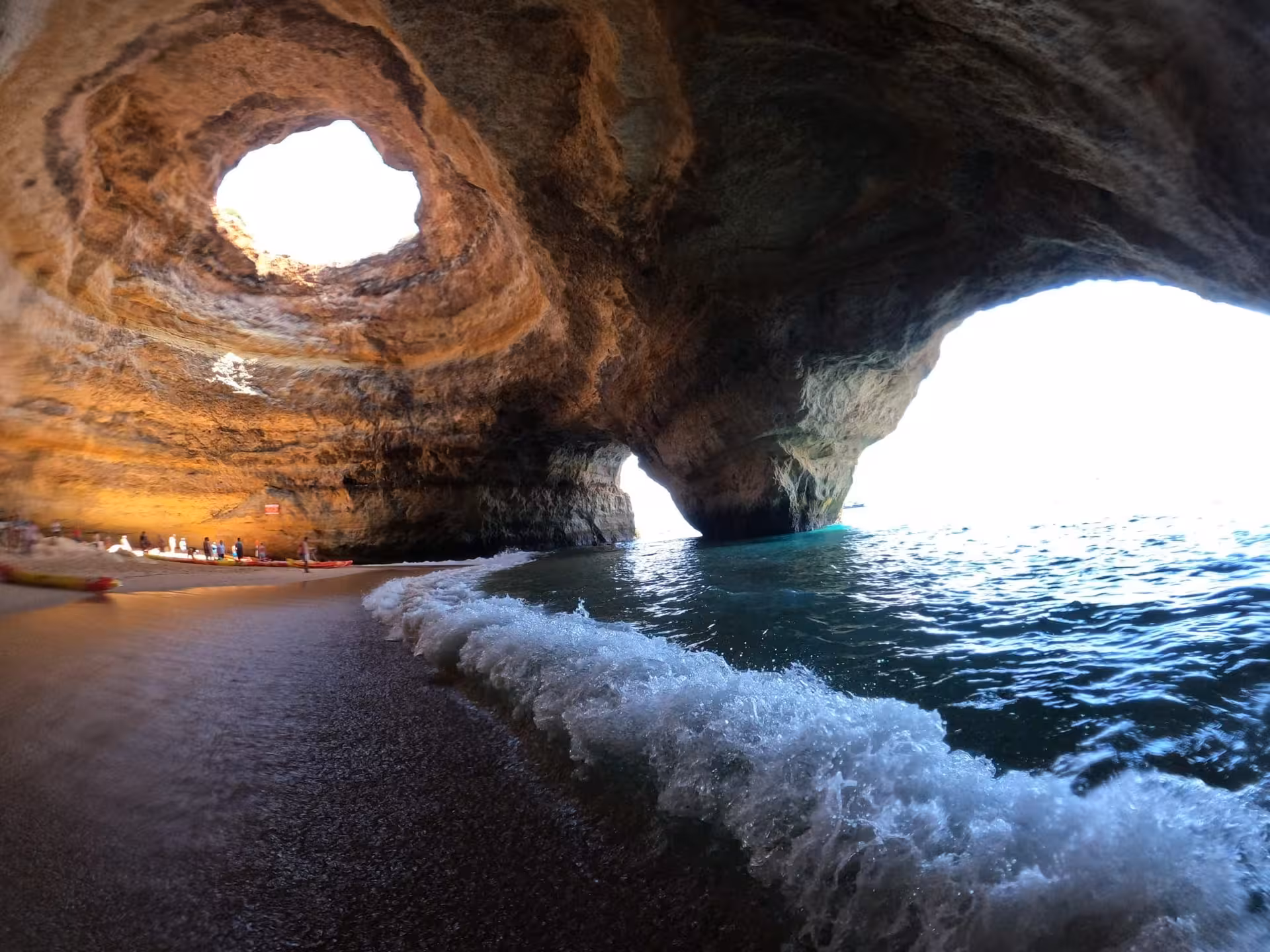 Benagil sea cave adventure with turquoise waves rolling onto a hidden Algarve beach under dramatic rock arches
