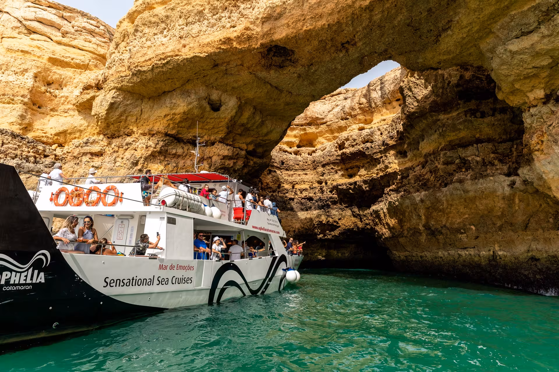 Ophelia catamaran navigates through Benagil cave, showcasing Algarve's breathtaking rock formations.