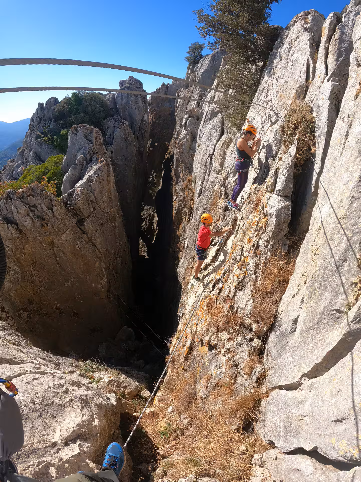 Two climbers tackling the vertical rock face of Benalauría Via Ferrata, with stunning Costa del Sol scenery.