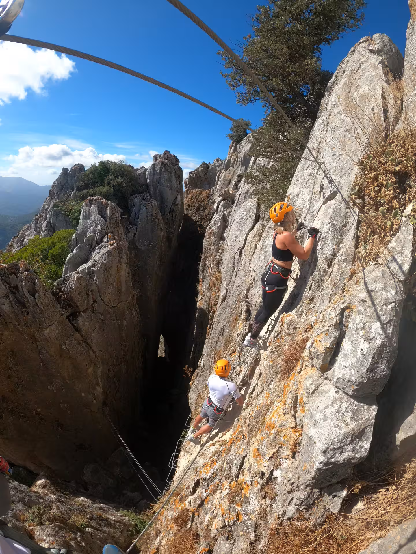 Adventurers climbing the rocky cliffs of Benalauría Via Ferrata, enjoying breathtaking Costa del Sol views.