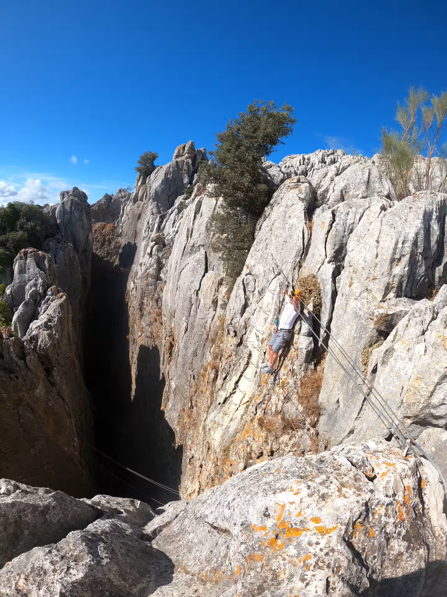 Thrill-seeker ascending a steep rock face on Benalauría's Via Ferrata, offering breathtaking Costa del Sol panoramas.